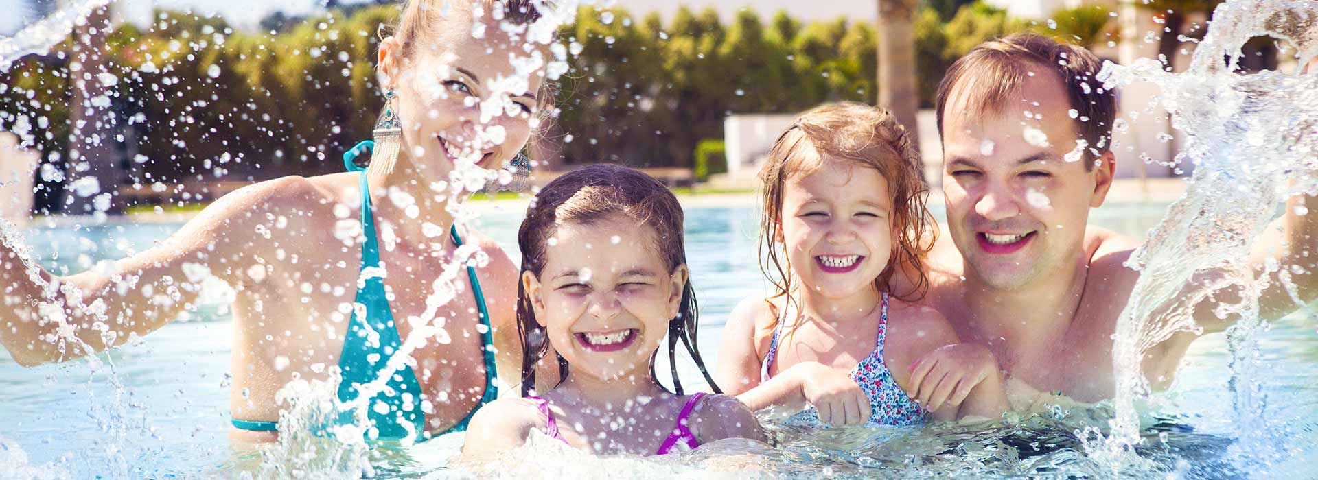 Une famille en train de rire, s'éclaboussant dans la piscine.