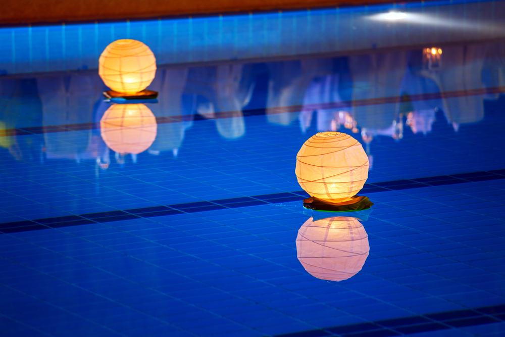 Piscine éclairée par des lumières flottantes.