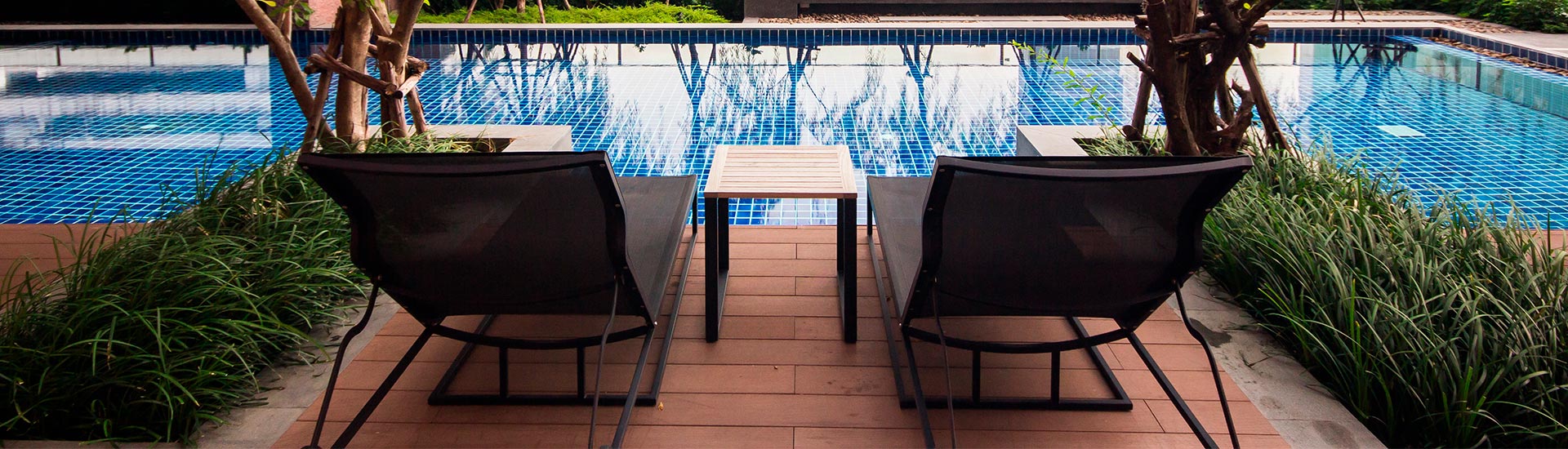 Deux transats en bois face à une piscine.