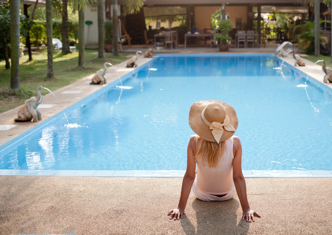 Femme assise au bord d'une piscine.