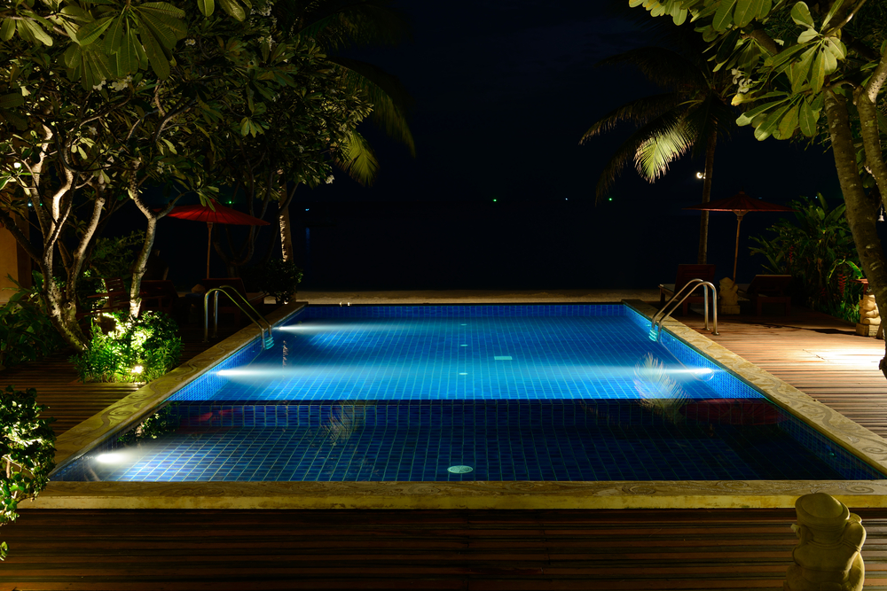 Piscine de nuit, éclairée par des lumières sous-marines.