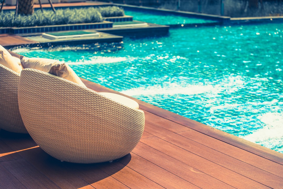 Petits sièges en osier près d'une piscine.